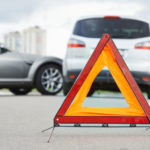 Accident or crash with two automobile. Road warning triangle sign in focus