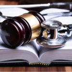 Close-up Of Stethoscope And Mallet Over Opened Law Book