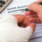 filling up a work injury claim form with a wrapped hand