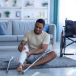 black man with injured leg sitting on floor after falling down