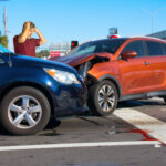 Two cars have crashed wrecked into each other at intersection with very upset man driver