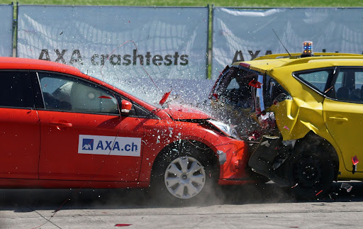 red car crashing into yellow car, resulting in car accident and shattering glass